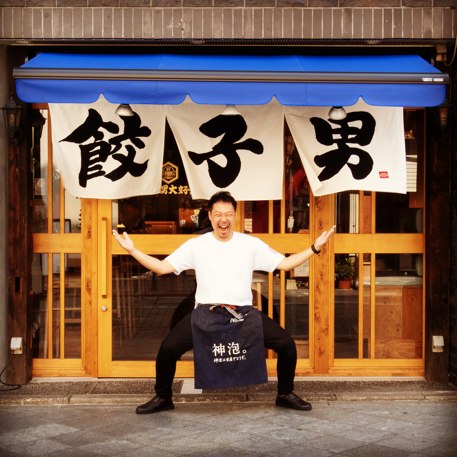 看板を指差して笑う店長